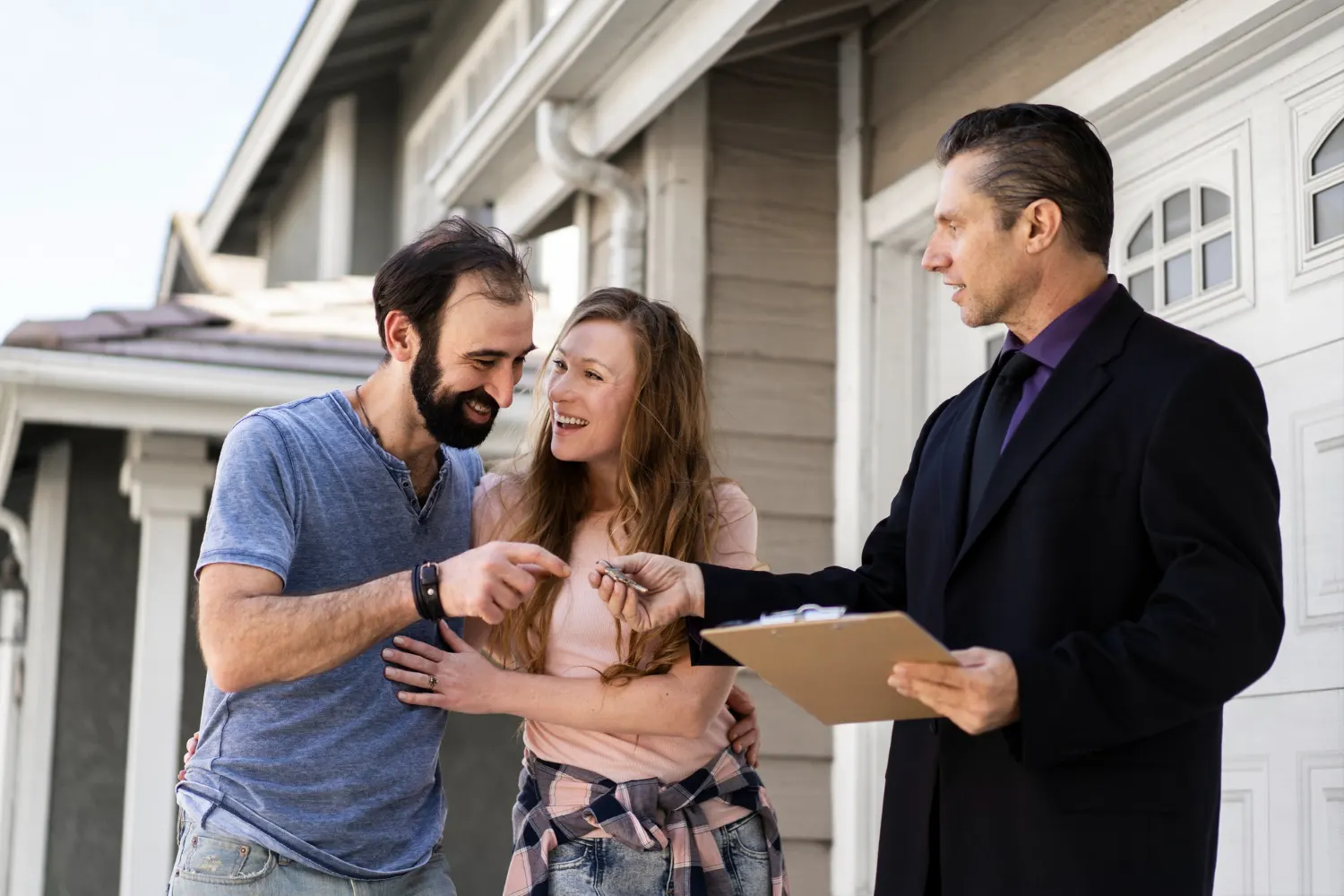 Happy couple receiving house keys from real estate agent after signing guarantor agreement in UK