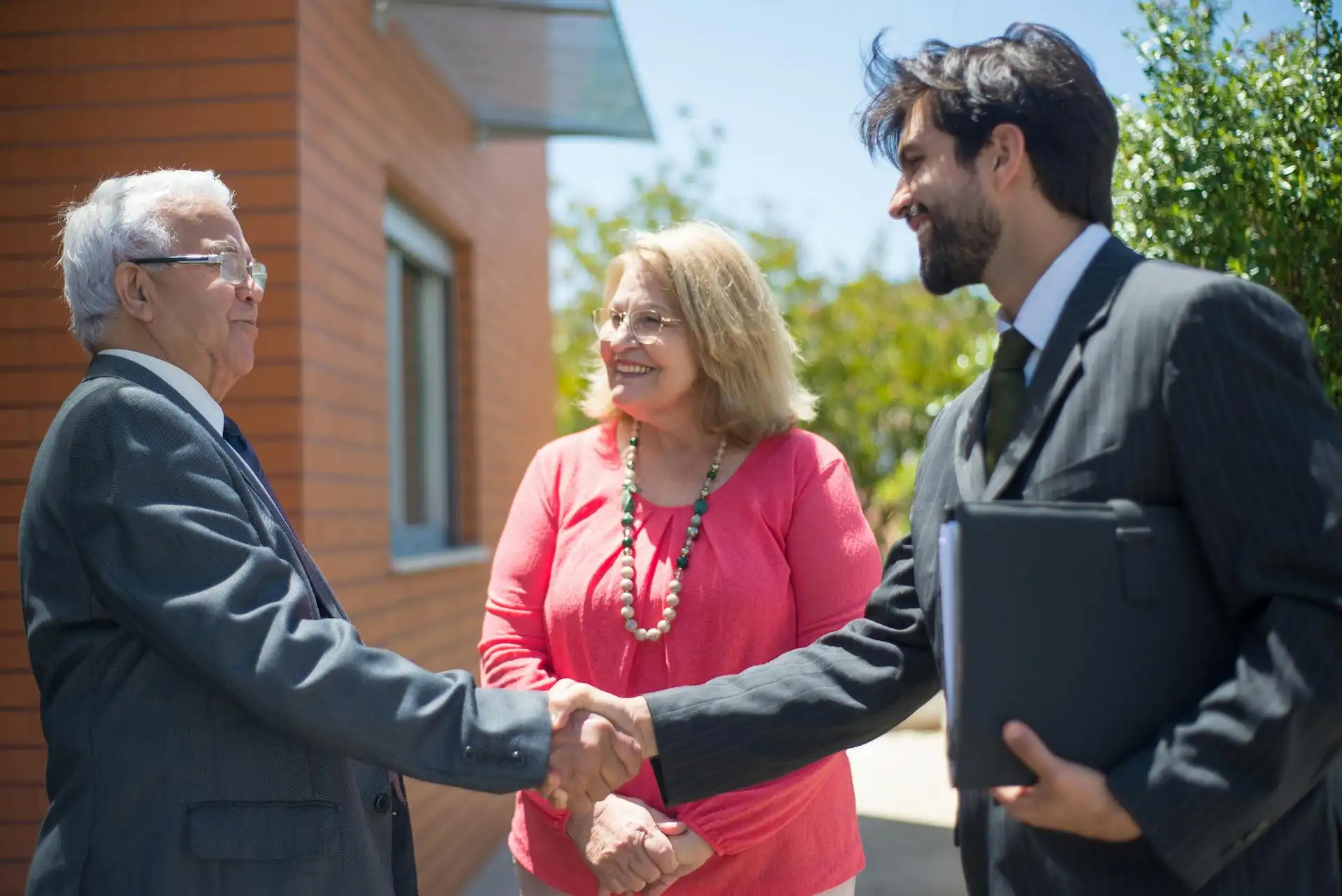 Professional lawyer shaking hands with senior landlord clients outside UK property - trusted legal services