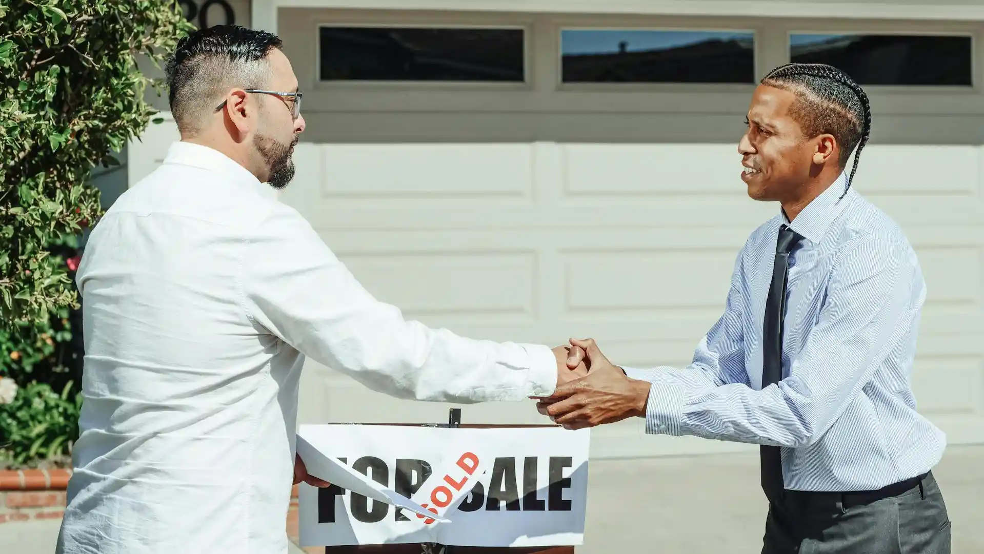 Professional handshake between landlord and tenant completing property sale transaction with sold sign - UK property law services